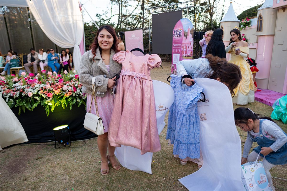 Mamás sostienen vestidos de niña en perchas durante el lanzamiento