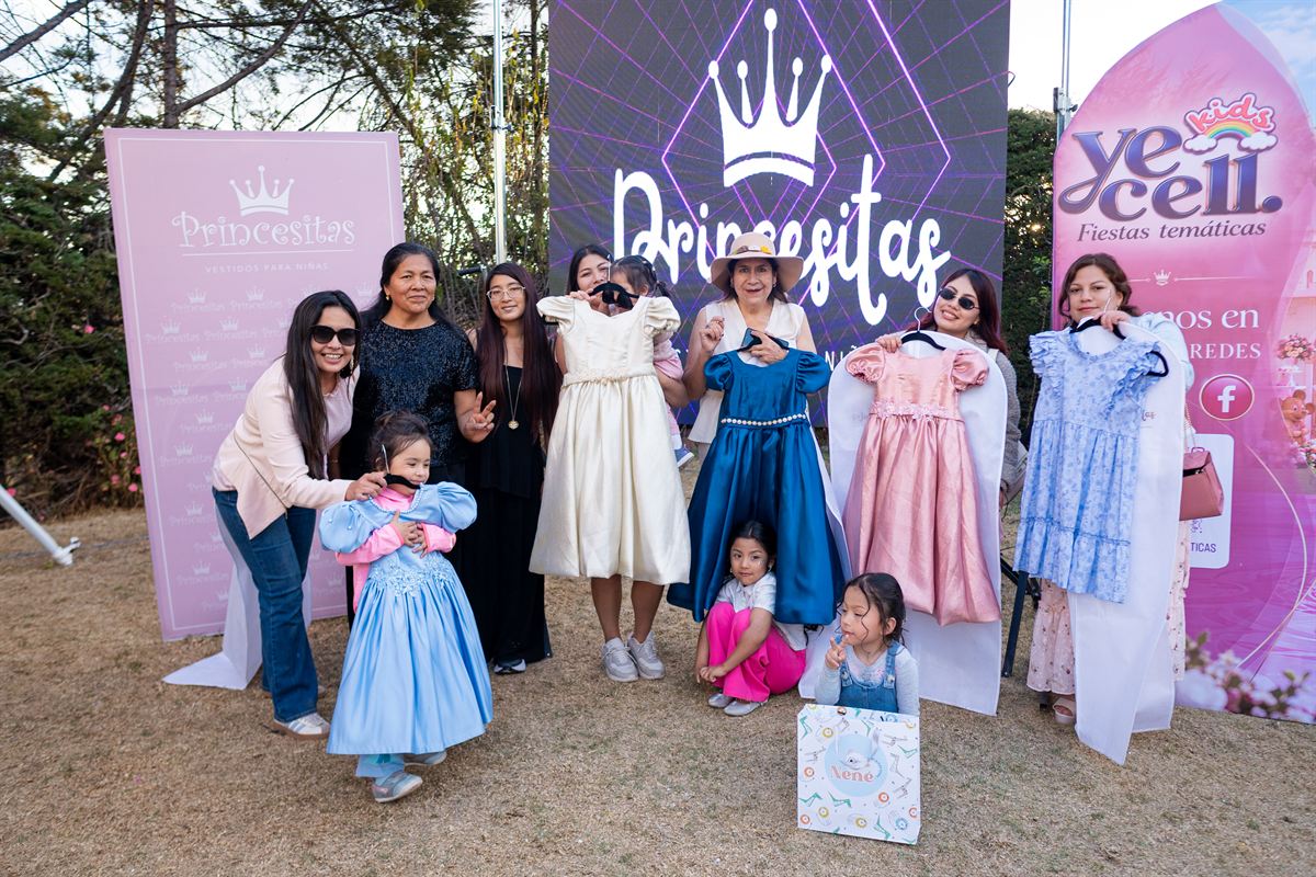 Mamás y niñas con vestidos en perchas frente al letrero de Princesitas